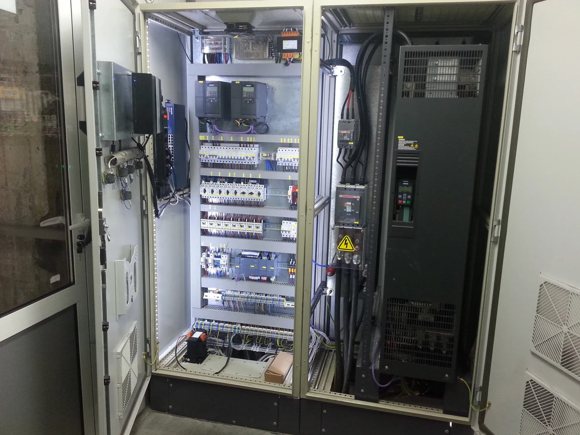 Open control cabinet showing its wiring, breakers and control components.