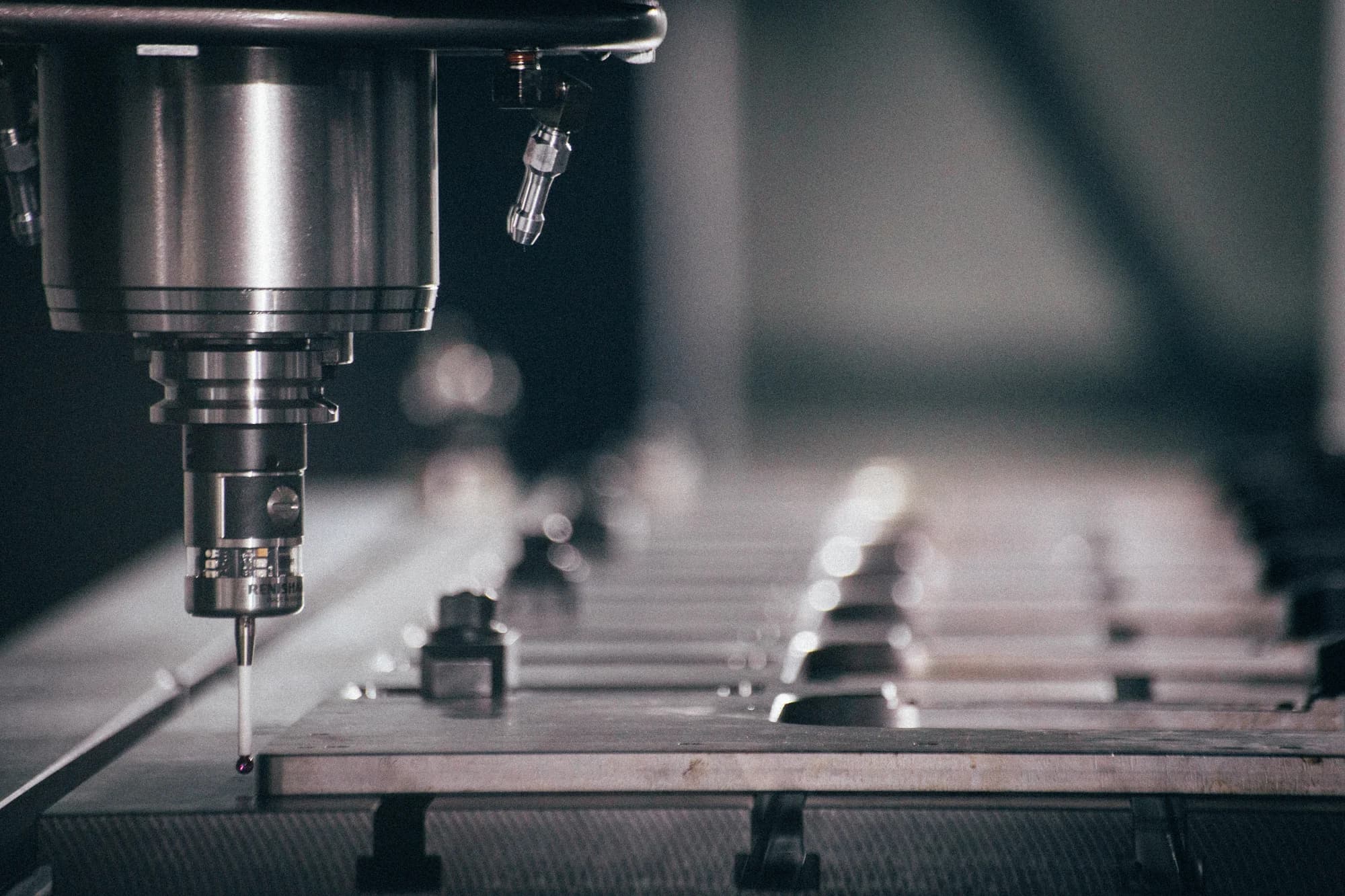 Cutting tool above a row of clamped components on the machine bed.