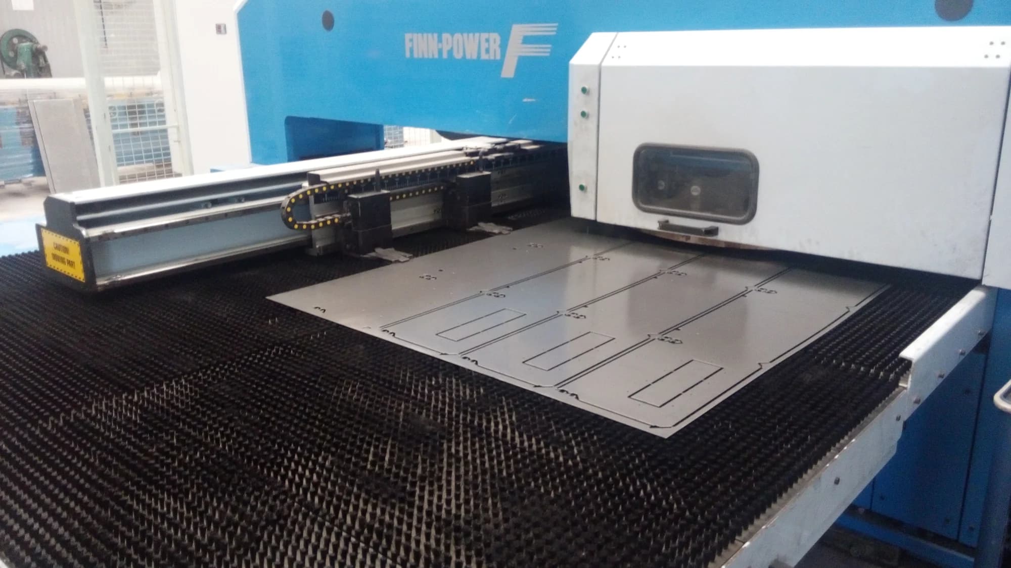 Punching table with a metal sheet positioned on the brush bed.
