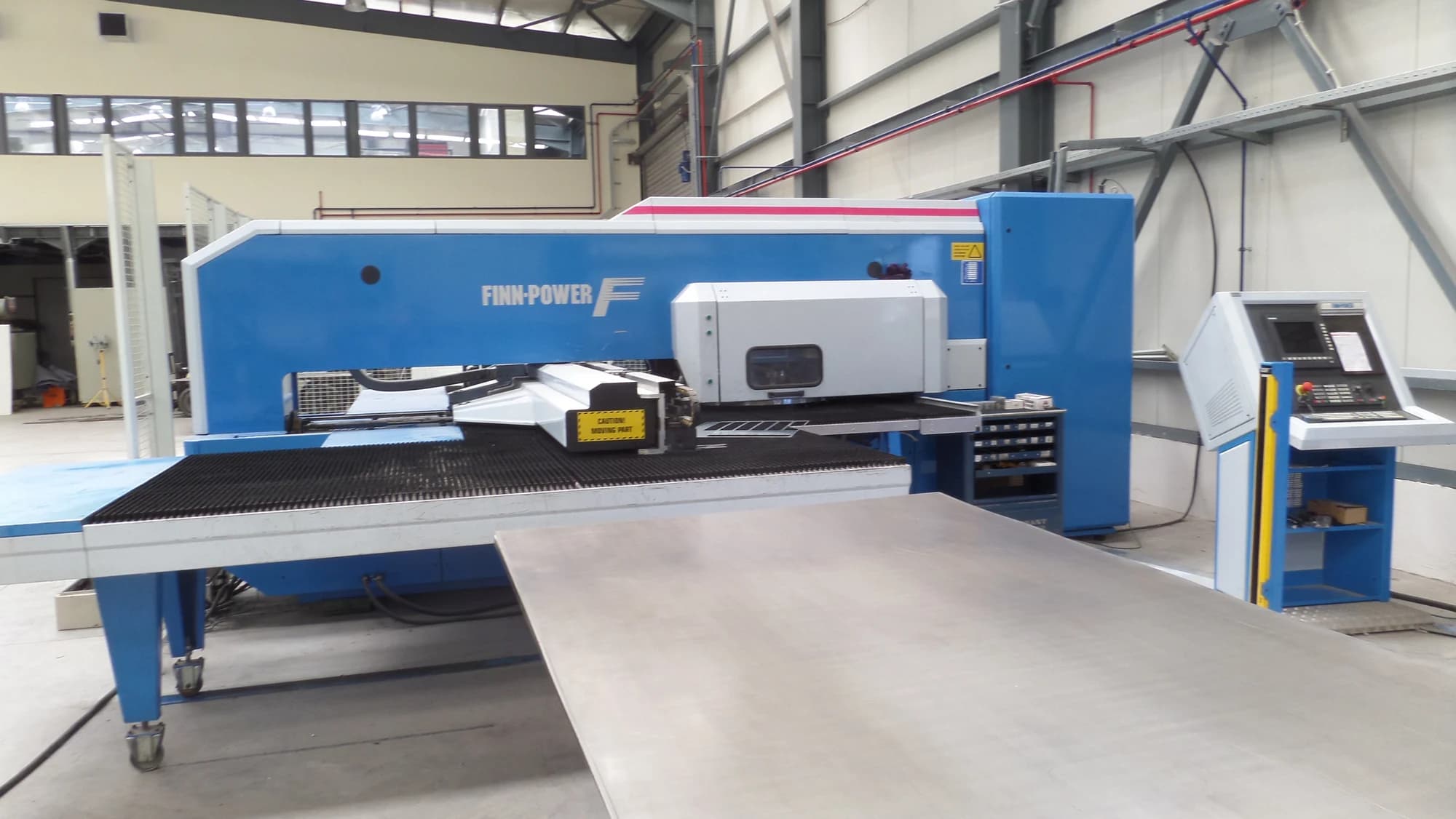 Wide view of the punching machine alongside its sheet handling table.